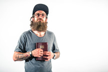 man with tattoos holding a Bible to his chest 