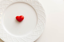A heart shaped tomato h'or d'oeuvre on a white plate.
