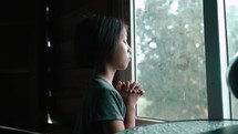 Asian girl praying in window