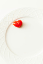 A heart shaped tomato on a white plate.