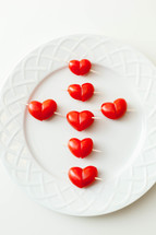 Heart shaped tomato h'or d'oeuvres on a white plate.