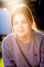sunlight on the face of a praying teen girl 