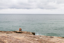 a man sitting on a shore contemplating 