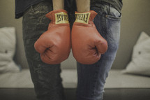 couple wearing boxing gloves standing back to back 