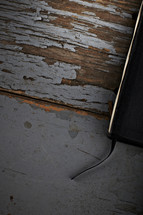 The edge of a Bible and bookmark - sitting on a wooden table