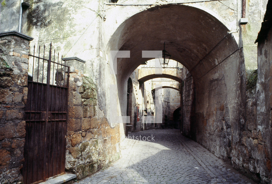 an alley in an ancient city with arches, stone walls and pavement