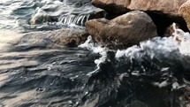 water lapping onto rocks at a harbor 