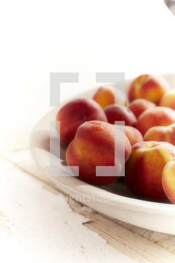 A cluster of peaches set in a bowl.