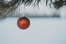 single red ornament hanging on a branch 