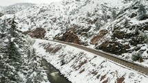 Drone footage of a highway and a river in the snowy Colorado mountains.