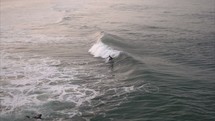 Surfer catches wave while another surfer paddles out - Surf Shoot