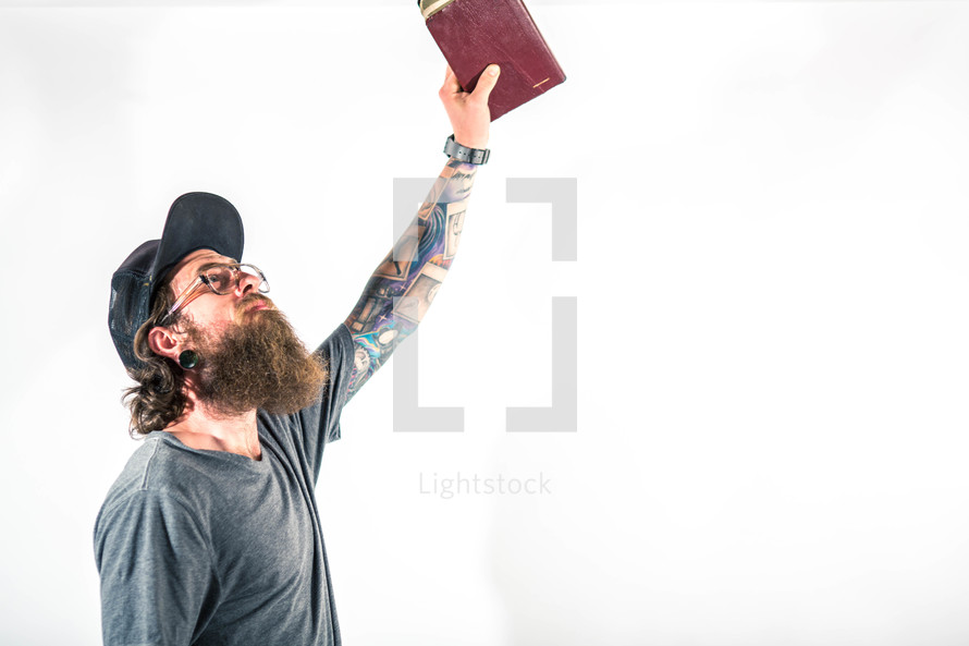 man holding a raised Bible to God 