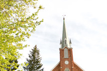 brick church with steeple and spring trees 