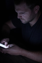 a man texting in darkness 