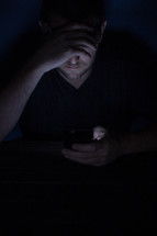 a man texting in darkness 