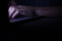 a man looking at a computer screen at night 