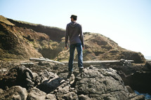 man standing on rocks on a shore 