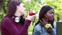 teens eating apples and looking at a computer screen 