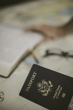 Bible, reading glasses, and passport on a map, missions preparation 