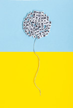 Balloon made of letters on a yellow and blue background. Conceptual image regarding literature, language and freedom of expression.
