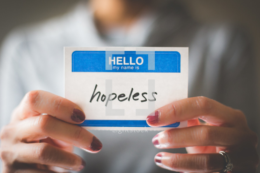 woman holding a name tag with the word hopeless 