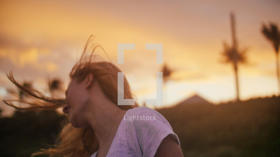 a woman tossing her hair at sunset 