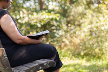 a woman sitting on a bench reading a Bible 