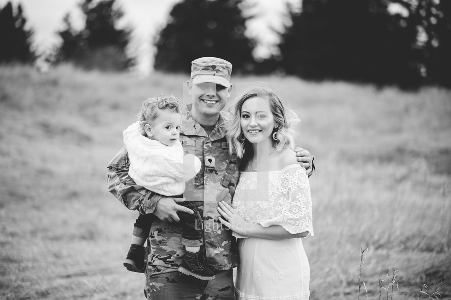 soldier in a field standing with his family 