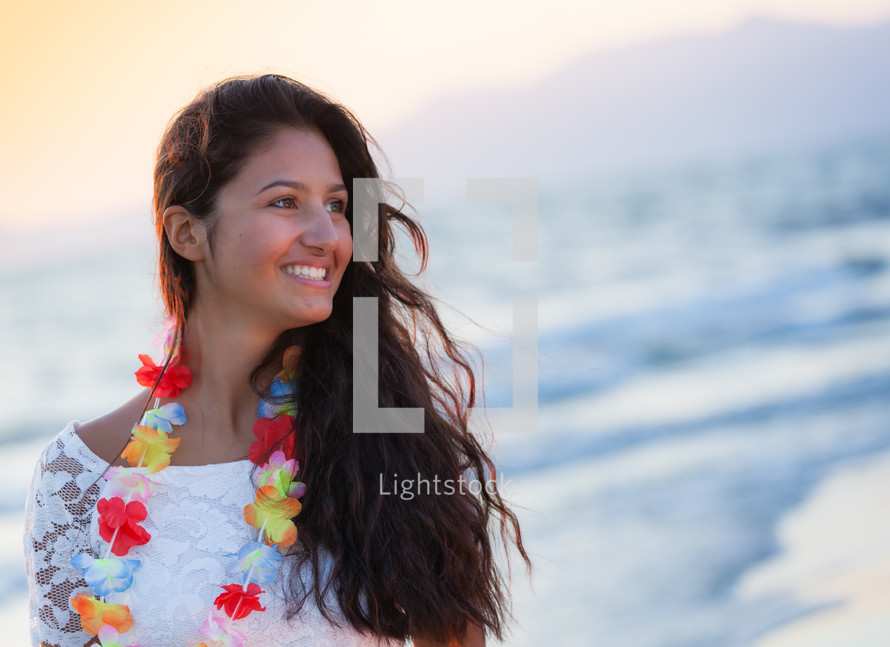 young teenager with a white dress on the beach at sunset.