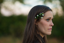 profile shot of woman with flowers behind her ear 
