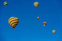 Brightly colored hot air  balloons in a blue sky.