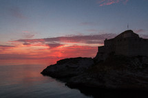 fortress walls along a shore at sunset 