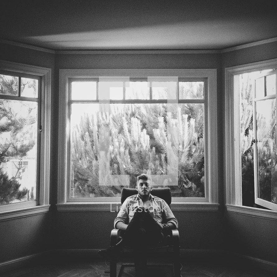 man sitting in a chair in front of a window