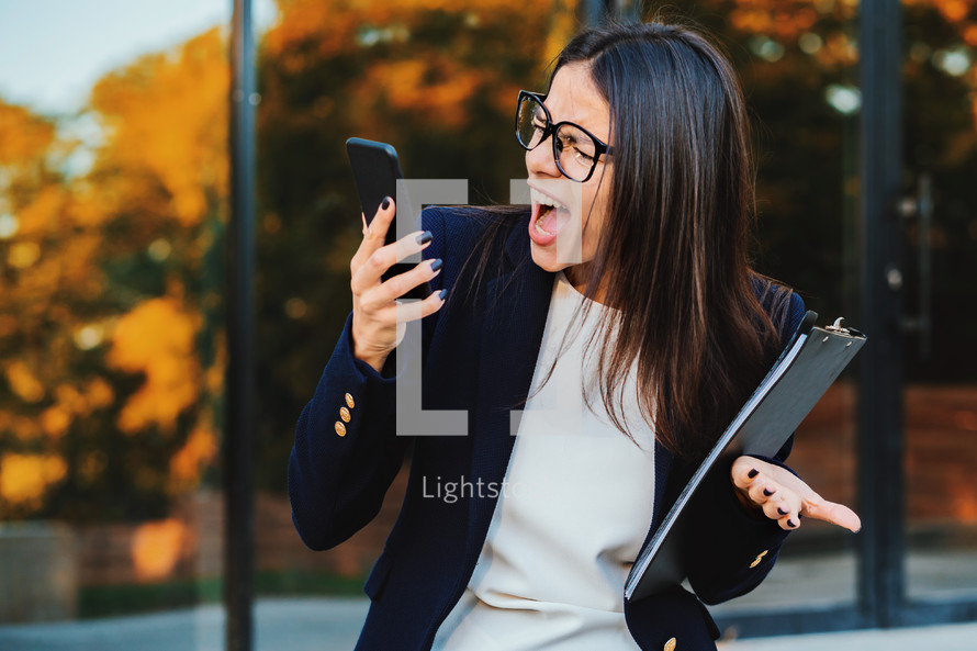 Businesswoman screaming on mobile phone. Having nervous breakdown at work, screaming in anger, stress management, mental distress problems, losing temper, reaction on failure.
