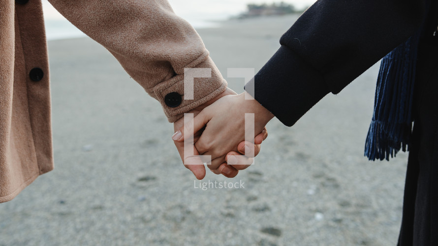Man and woman holding hands on the beach
