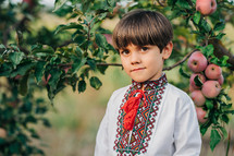 Portrait of handsome ukrainian boy in apple orchard. Child in traditional embroidery vyshyvanka shirt. Ukraine, freedom, national costume. High quality photo