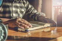 Young man reading a Bible on wooden table in morning at home