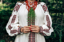 Authentic woman in traditional ukrainian costume with fern in forest. Lady in national dress - vyshyvanka, ancient coral beads. High quality photo