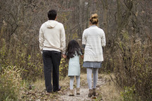 Family walking on a trail in a forest.