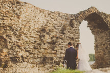 bride and groom standing in front of a stone wall 