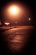 a glowing streetlight on a dark street at night 