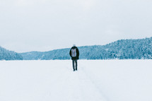a man walking in snow with his back to the camera 