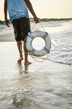 man carrying a life ring on a beach