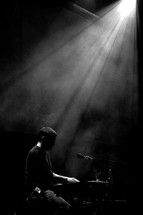 stage lights shining on a musician playing a keyboard