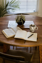 A Bible, journal, and coffee mug on a wood table 