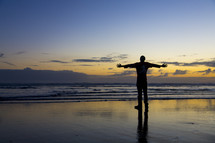 man standing on a beach with open arms 