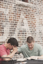 men praying and reading a Bible at a Bible study 