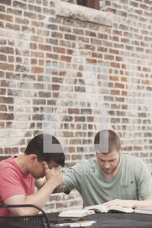 men praying and reading a Bible at a Bible study 