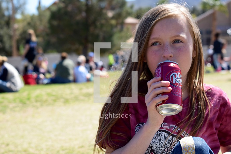 a child drinking a soda at an outdoor festival 