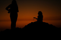 two women talking on a beach at sunset 